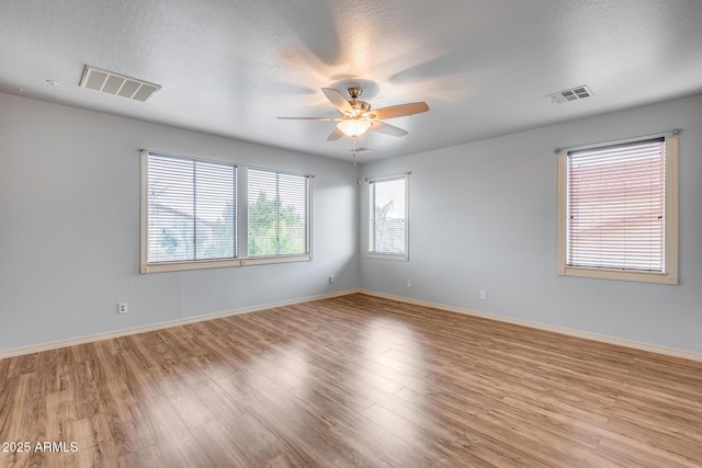 empty room featuring a textured ceiling, light hardwood / wood-style floors, and ceiling fan