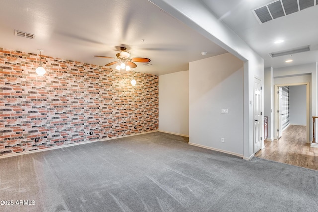 carpeted empty room featuring brick wall and ceiling fan