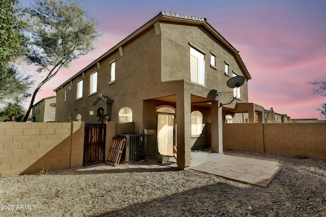 back house at dusk featuring cooling unit and a patio area