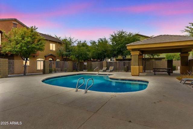 pool at dusk featuring a gazebo and a patio area