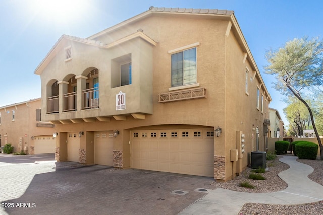 view of front facade with cooling unit, a garage, and a balcony