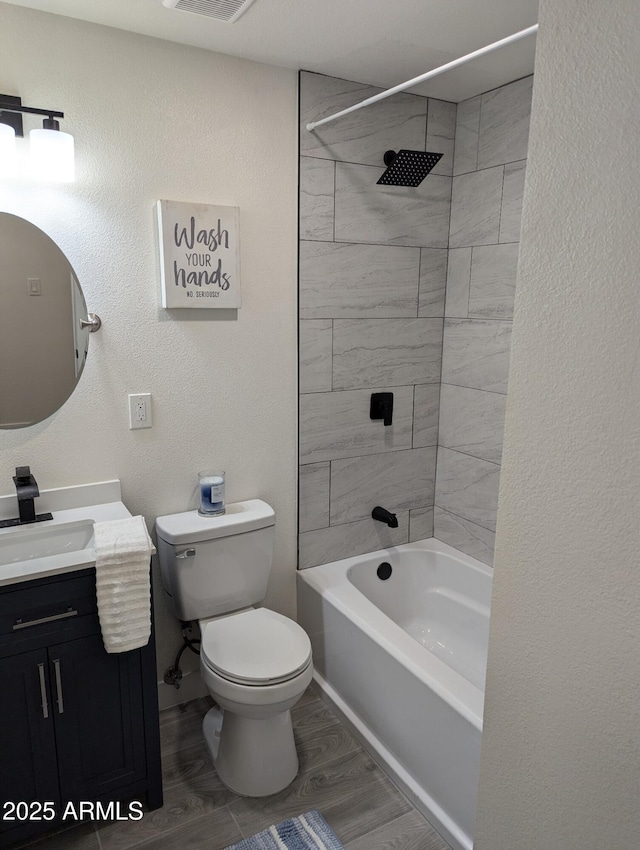 full bathroom with wood-type flooring, tiled shower / bath combo, vanity, and toilet