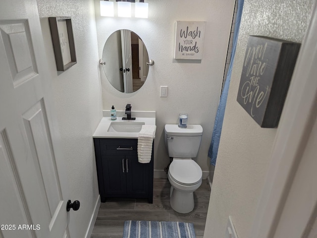 bathroom with toilet, vanity, and wood-type flooring