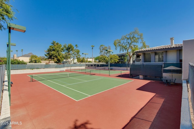 view of tennis court with community basketball court and fence