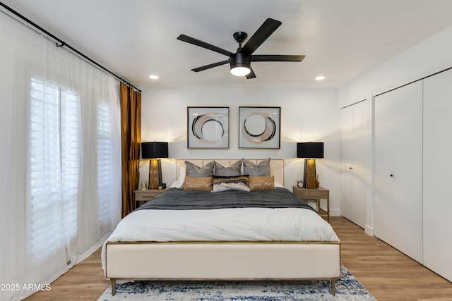 bedroom featuring recessed lighting, light wood-type flooring, multiple windows, and multiple closets