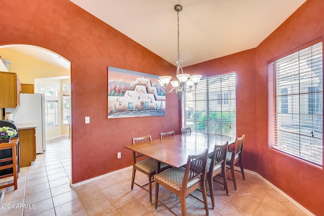 tiled dining space with a healthy amount of sunlight, a notable chandelier, and vaulted ceiling