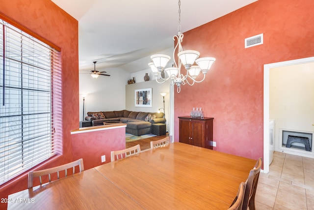 tiled dining area with ceiling fan with notable chandelier, a wealth of natural light, and lofted ceiling