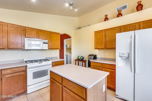 kitchen featuring white appliances, light tile flooring, lofted ceiling, washer / clothes dryer, and rail lighting