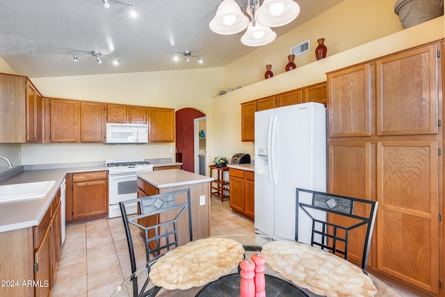 kitchen featuring white appliances, track lighting, lofted ceiling, sink, and a center island