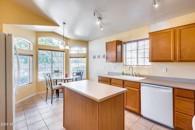 kitchen featuring white appliances, lofted ceiling, rail lighting, sink, and pendant lighting