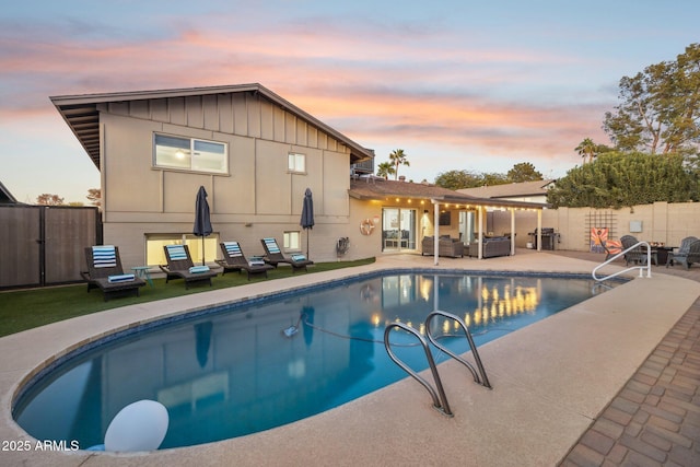 pool at dusk featuring an outdoor living space and a patio area