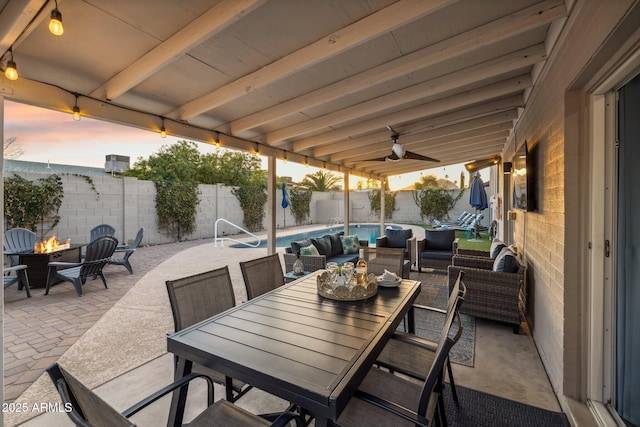 patio terrace at dusk featuring a fenced in pool, an outdoor living space with a fire pit, and ceiling fan