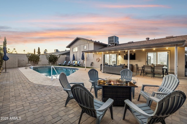 pool at dusk featuring an outdoor living space with a fire pit and a patio area