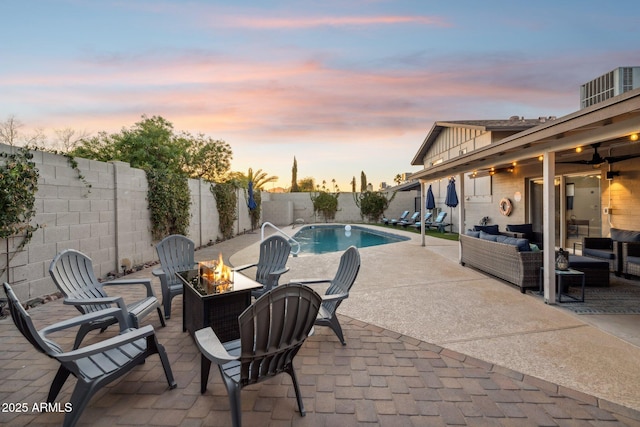 pool at dusk featuring cooling unit, a patio area, and an outdoor living space with a fire pit