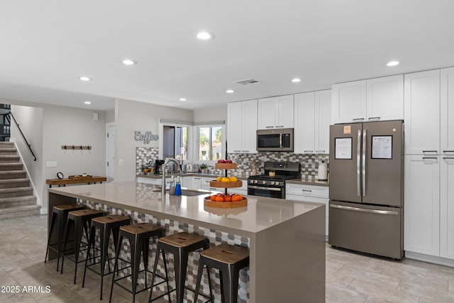 kitchen with stainless steel appliances, a breakfast bar, sink, and a center island with sink