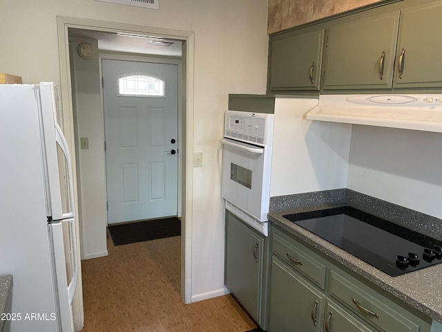 kitchen with extractor fan, light hardwood / wood-style flooring, white appliances, and green cabinetry