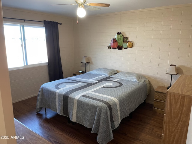 bedroom featuring brick wall, dark hardwood / wood-style floors, and ceiling fan