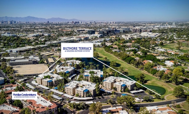 aerial view with golf course view, a water and mountain view, and a city view