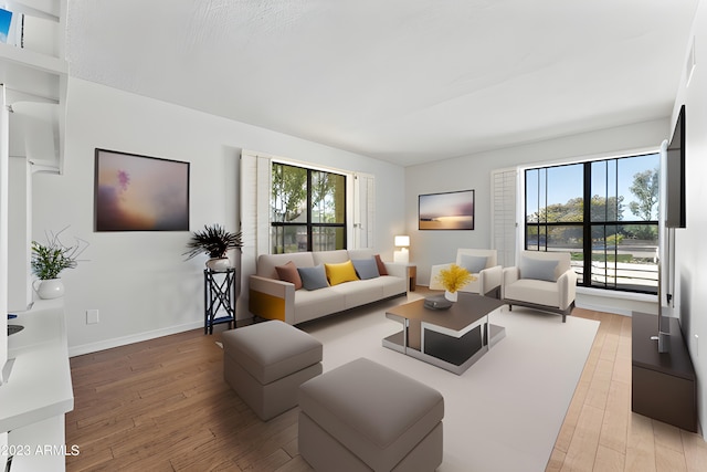 living area with plenty of natural light, light wood-style flooring, and baseboards