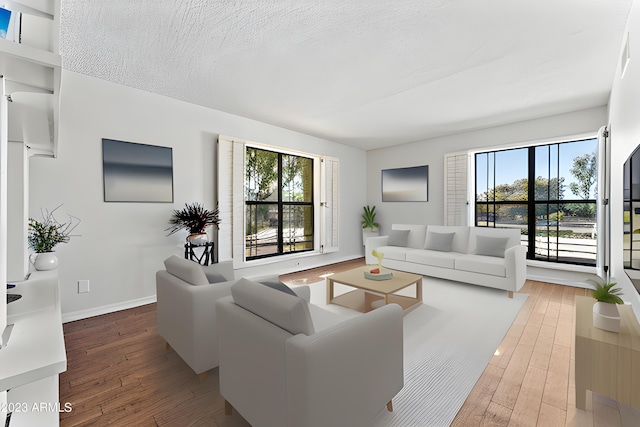 living room with wood-type flooring, a textured ceiling, and baseboards