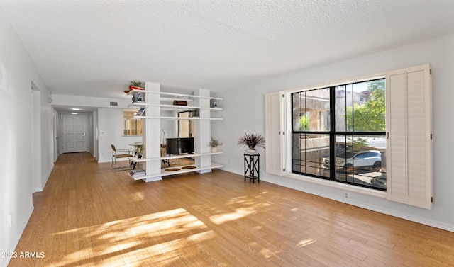 unfurnished living room featuring light wood finished floors, visible vents, and a textured ceiling