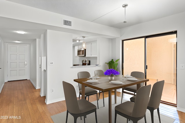 dining space with light wood-style floors, baseboards, and visible vents