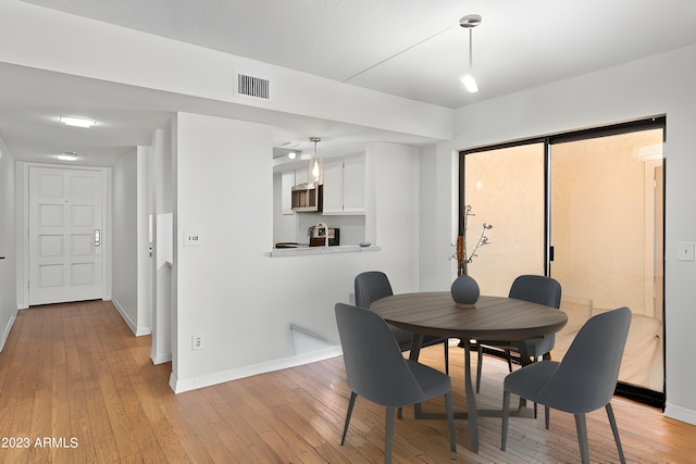 dining space with visible vents, light wood-style flooring, and baseboards