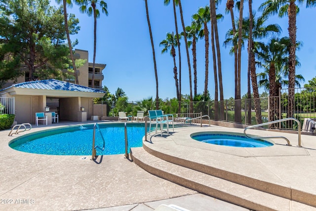 community pool featuring a patio area, fence, and a hot tub