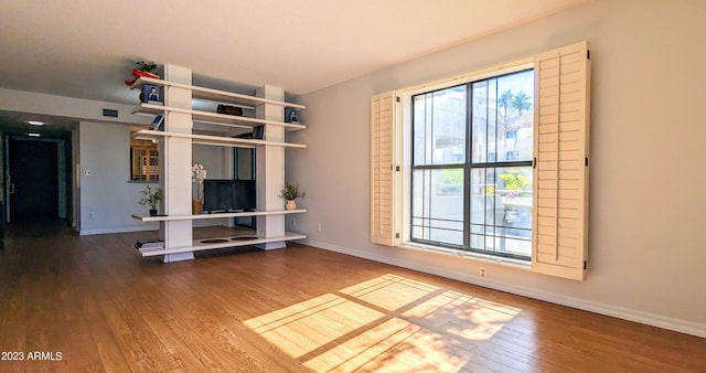 unfurnished living room with wood finished floors, visible vents, and baseboards