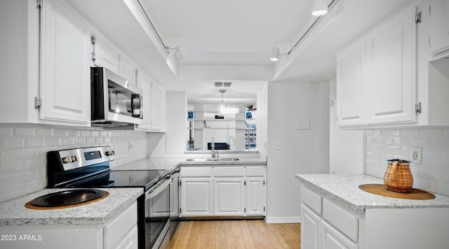 kitchen with light wood finished floors, visible vents, white cabinets, stainless steel appliances, and a sink