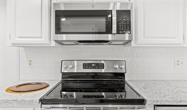 kitchen featuring light stone counters, appliances with stainless steel finishes, white cabinets, and decorative backsplash