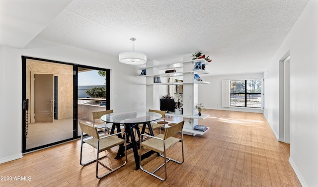 dining area featuring baseboards, a textured ceiling, and light wood finished floors