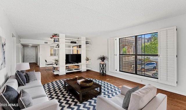 living room with visible vents, a textured ceiling, baseboards, and wood finished floors