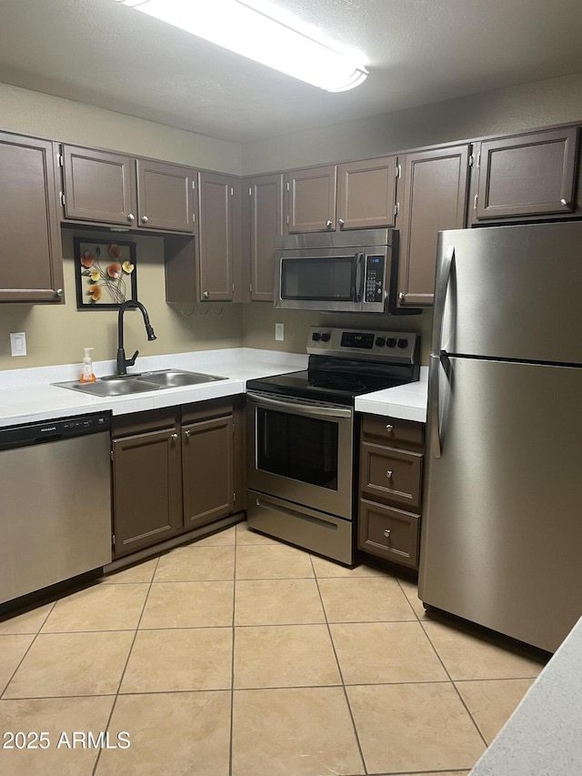 kitchen featuring a sink, appliances with stainless steel finishes, light tile patterned flooring, and light countertops