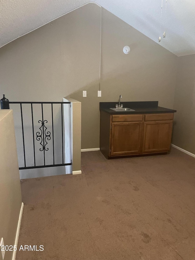 interior space featuring baseboards, vaulted ceiling, light carpet, and a sink