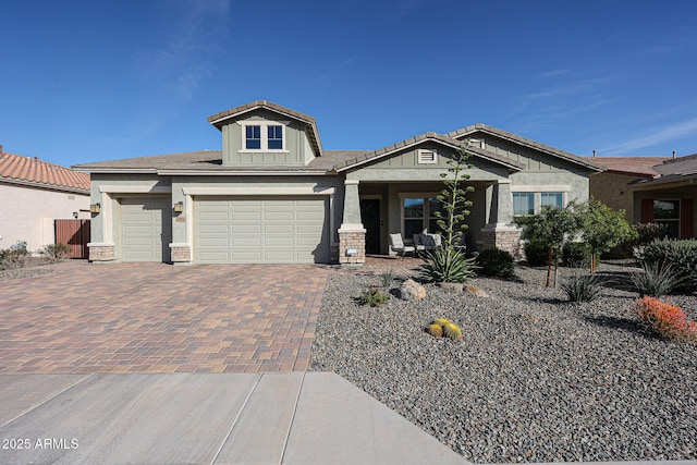 craftsman-style home with stone siding, a tiled roof, decorative driveway, and stucco siding