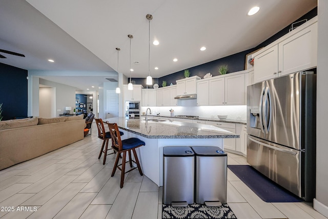 kitchen with stainless steel appliances, open floor plan, white cabinetry, and a kitchen breakfast bar