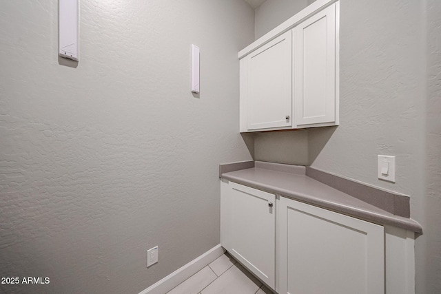 laundry room featuring a textured wall, baseboards, and light tile patterned floors