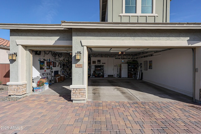 garage featuring freestanding refrigerator and decorative driveway