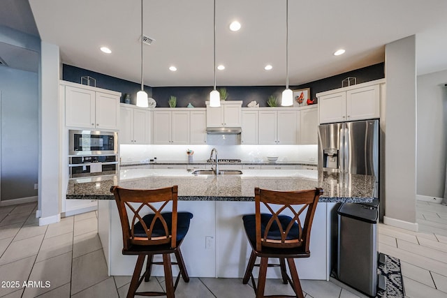 kitchen with appliances with stainless steel finishes, a sink, white cabinets, and decorative backsplash