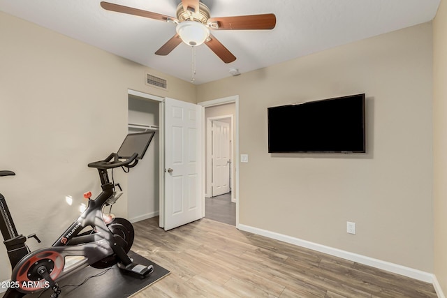 exercise room featuring ceiling fan and light wood-type flooring