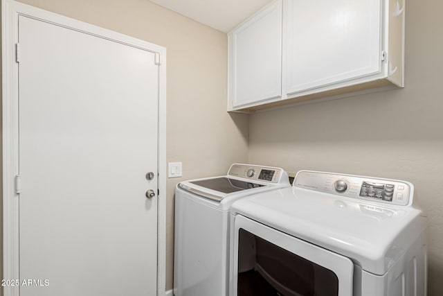 clothes washing area with cabinets and washer and dryer