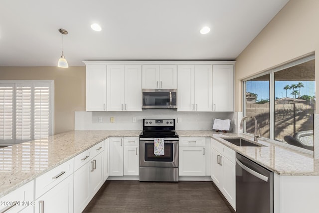 kitchen with stainless steel appliances, white cabinetry, sink, and decorative light fixtures