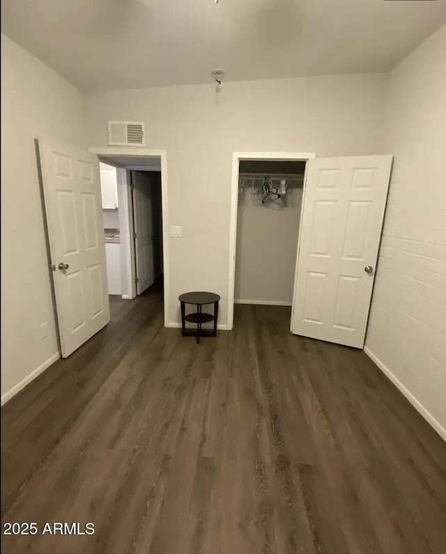 unfurnished bedroom with dark wood-style floors, a closet, visible vents, and baseboards