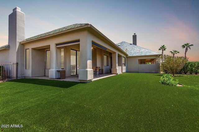 16540 E El Lago Blvd Unit 2, Fountain Hills, AZ 85268 - back of house at dusk with a chimney, stucco siding, and a patio