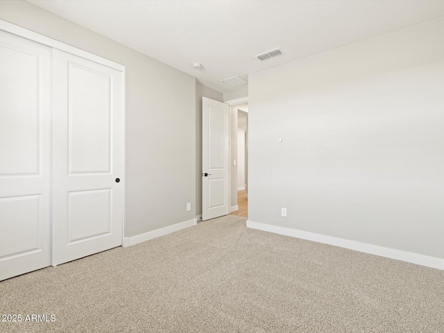 unfurnished bedroom featuring light carpet and a closet