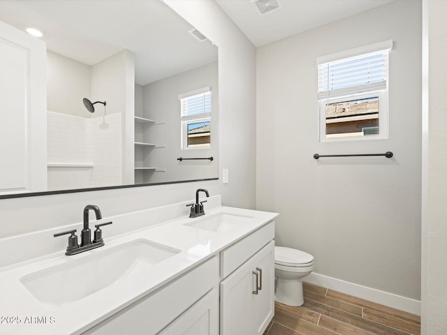 bathroom with vanity, a wealth of natural light, toilet, and walk in shower