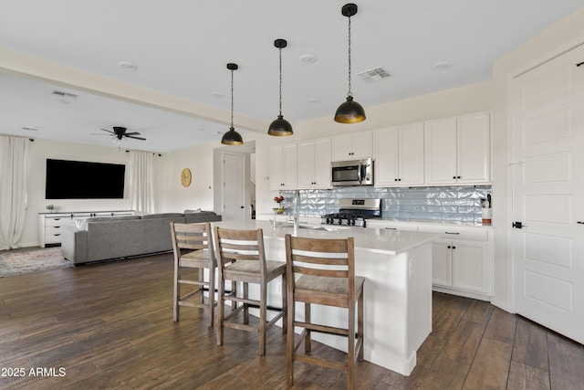 1800 S Jesse Pl, Chandler, AZ 85286 - kitchen with appliances with stainless steel finishes, dark wood-style flooring, light countertops, white cabinetry, and backsplash