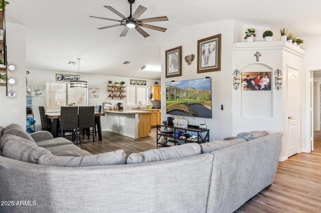 living room featuring hardwood / wood-style flooring, vaulted ceiling, ceiling fan, and sink