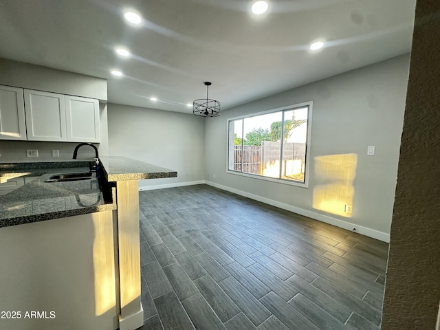 4902 S Fair Ln, Tempe, AZ 85282 - kitchen with a sink, dark stone counters, baseboards, white cabinets, and dark wood-type flooring